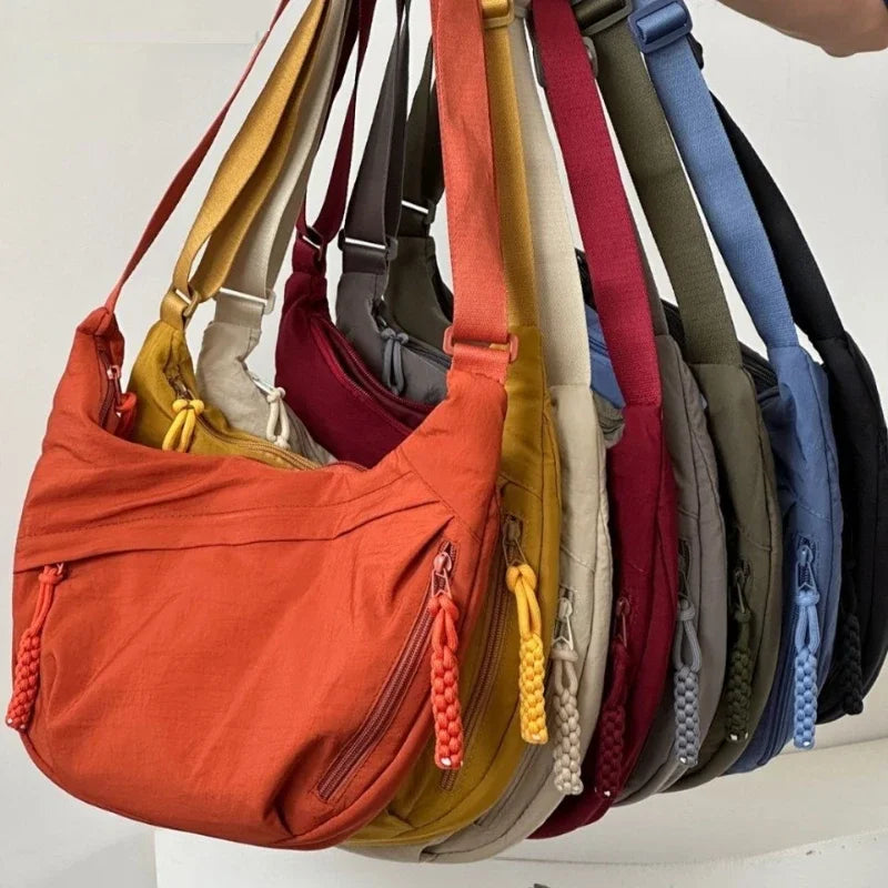 A collection of soft nylon crossbody shoulder bags in various colors including orange, beige, maroon, and blue.