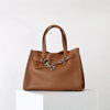 A brown genuine leather women's shoulder tote bag with a top handle resting on a white surface.