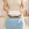 Una persona sostiene una bolsa de almuerzo acolchada azul aislada con un contenedor transparente, mostrando el producto.