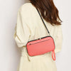 A woman holds a pink passport organizer pouch against a cream-colored jacket.