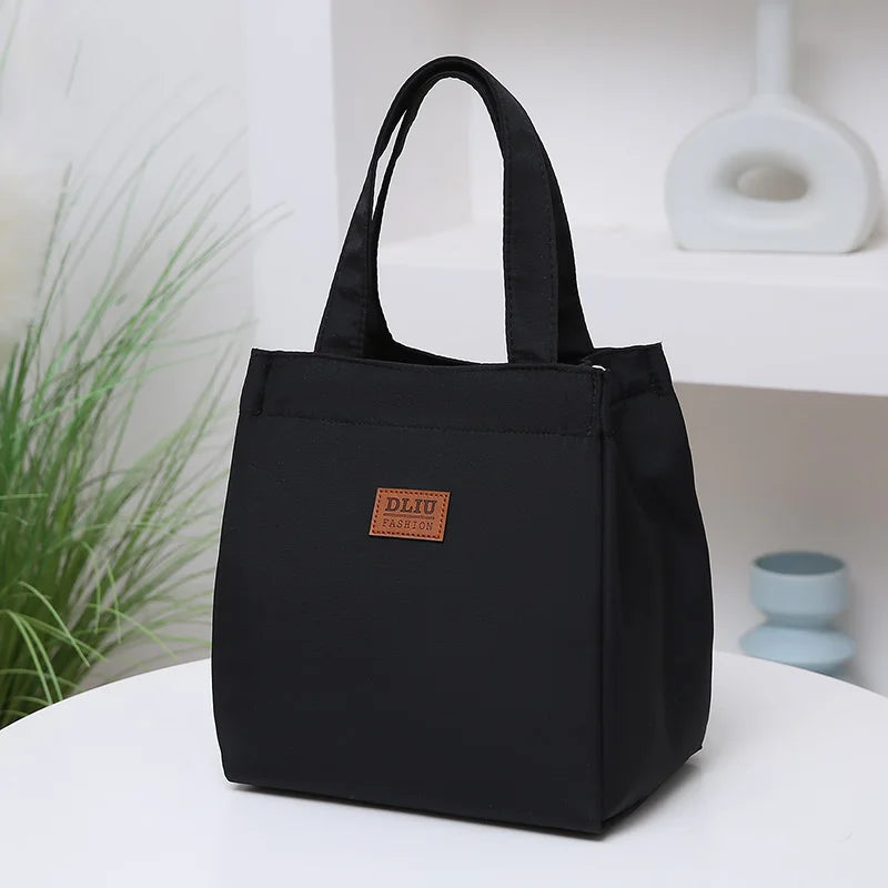 A black durable aluminum foil insulated lunch bag with a fabric handle resting on a white surface.