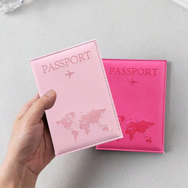 Une main tient une couverture de passeport en cuir PU rose avec un design de carte du monde.