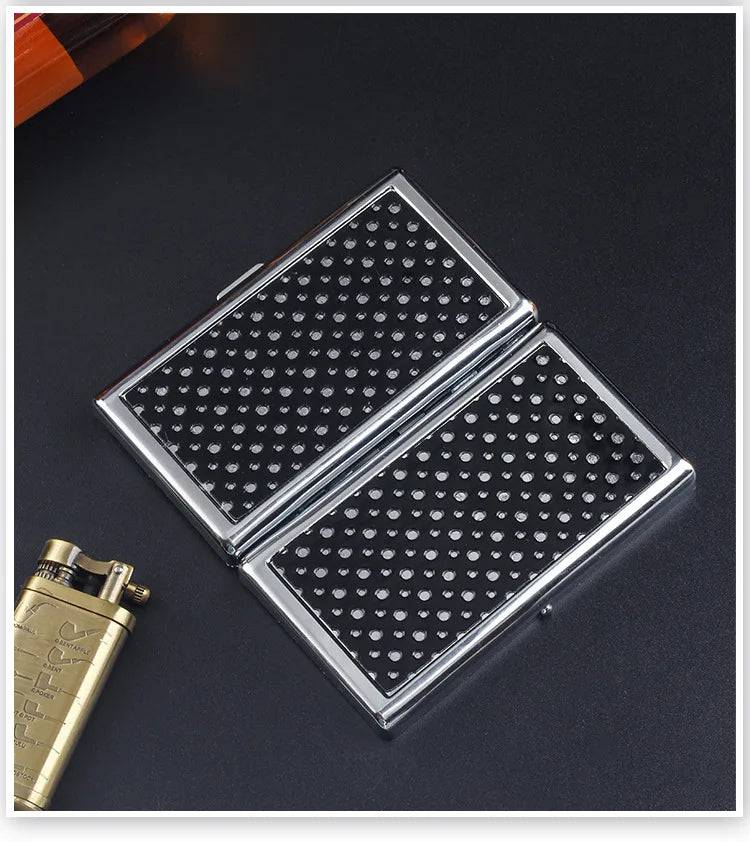 A silver metal cigarette case holder with a diamond pattern is shown on a dark surface.