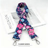 A floral patterned fabric strap with a silver buckle is displayed on a white box.