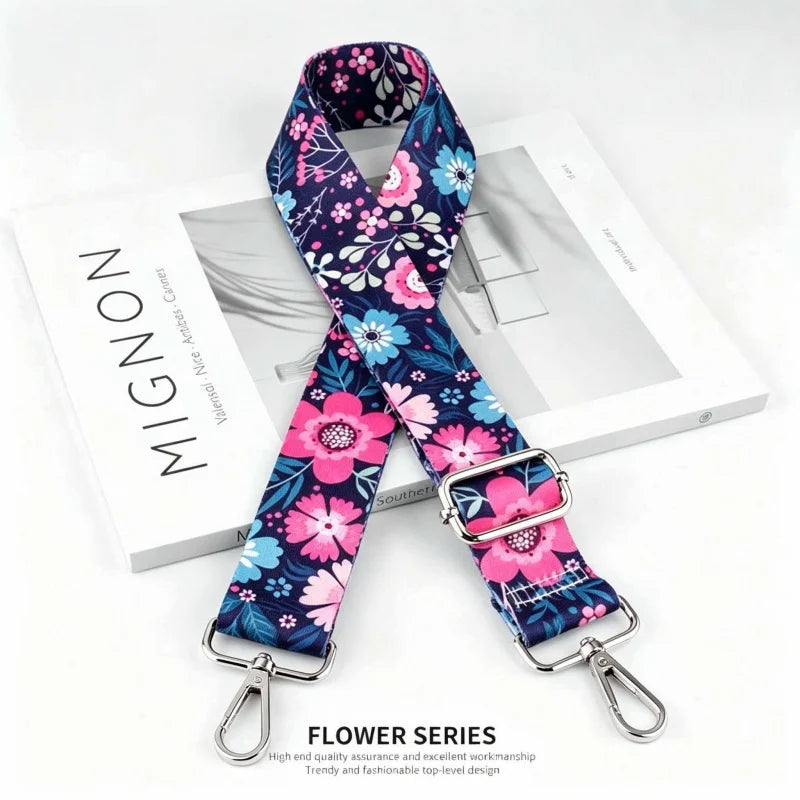 A floral patterned fabric strap with a silver buckle is displayed on a white box.