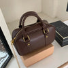 A dark brown vintage PU leather shoulder bag with gold hardware resting on a light cardboard box.