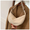 A beige women's preppy sling crossbody bag is shown being worn under a tan coat.