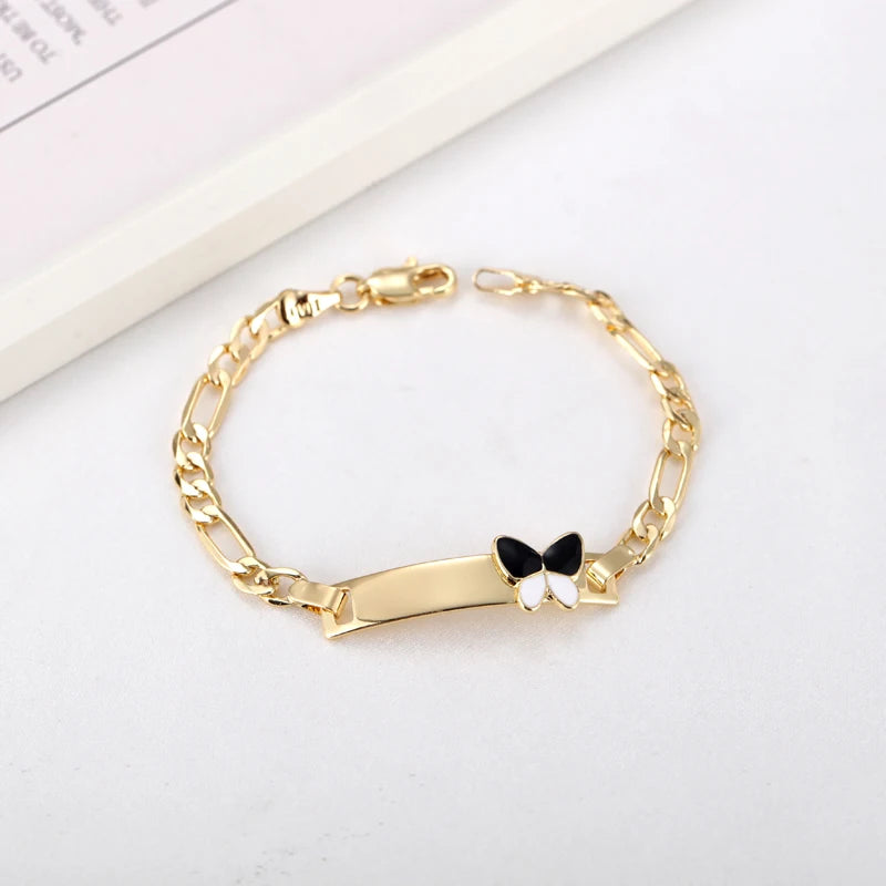 A gold-colored chain bracelet with a black butterfly charm on a white background.