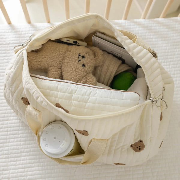 Una bolsa de almacenamiento de color crema forrada con un oso de peluche y una tableta dentro.