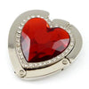 A heart-shaped red gemstone pendant set in silver metal with surrounding clear stones.