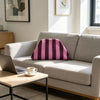 A pink and purple striped knit cloud makeup bag resting on a light gray sofa.
