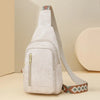 A light beige PU leather crossbody sling bag with a zipper and patterned strap is shown on a neutral background.
