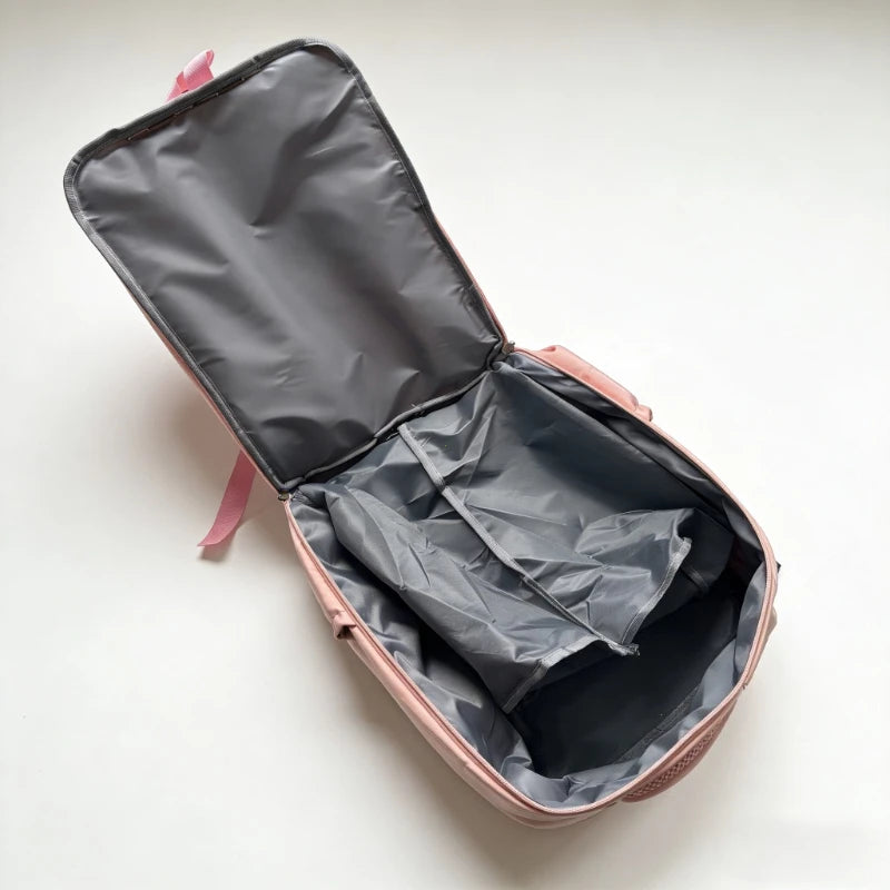 A pink compact travel backpack with a dark gray interior lining is shown open.