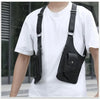 Black concealed underarm travel wallet with a phone pocket worn across the chest on a white t-shirt.