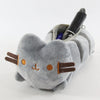 A soft gray plush cat storage pouch with orange facial markings and a black pen inside.