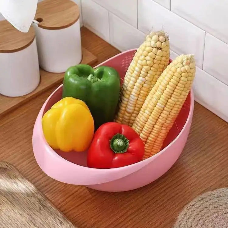 A pink plastic basket filled with fresh vegetables including green bell pepper and corn on the cob.