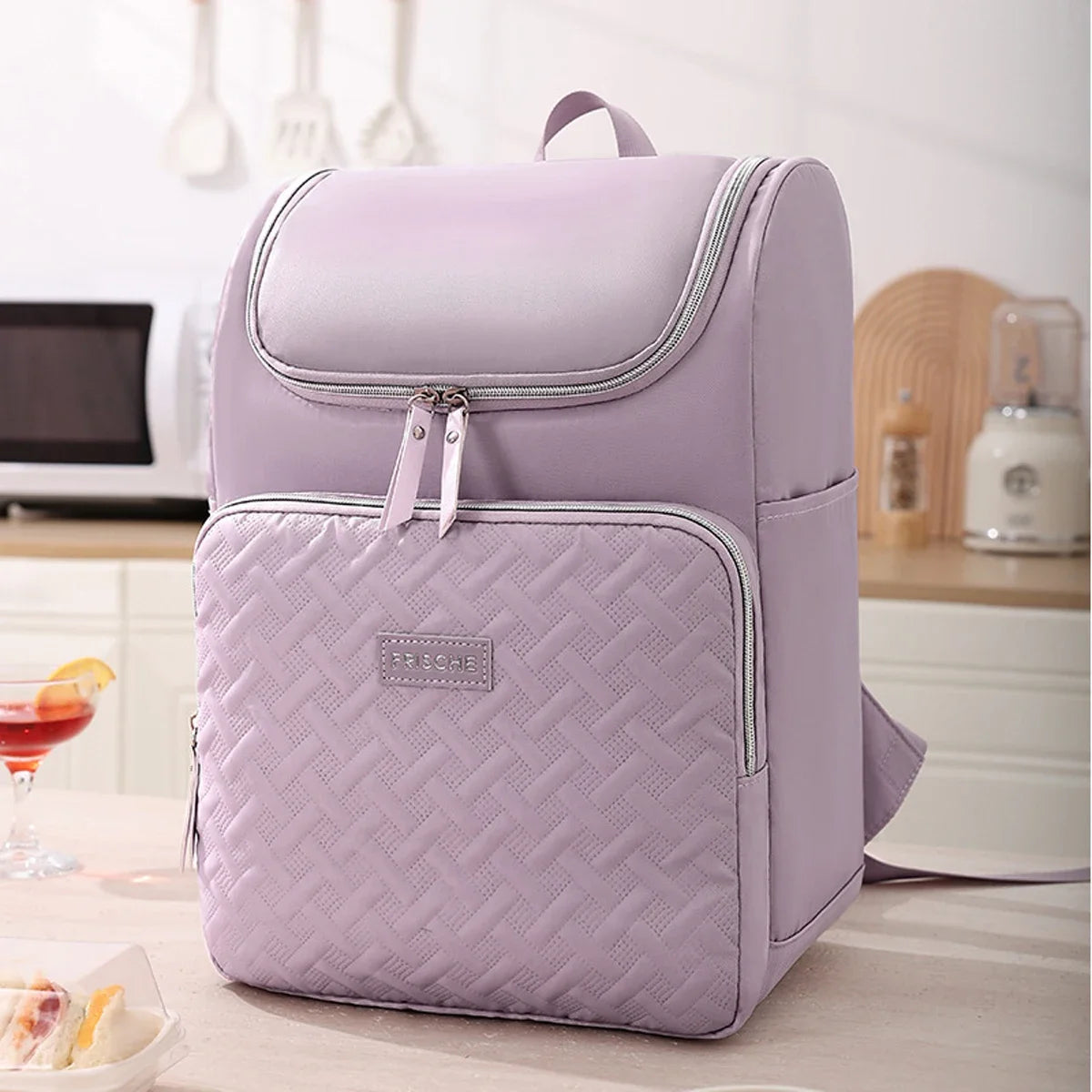 A light purple insulated travel backpack with a zippered pocket and quilted texture resting on a table.