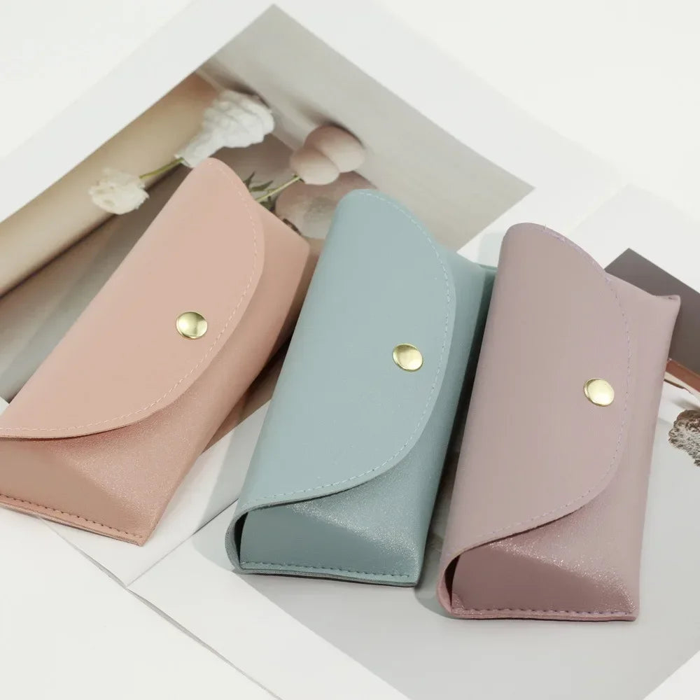 A light pink PU leather hard shell sunglasses case is shown resting on a white surface.