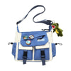 Bolso cruz de nylon casual azul y blanco con un dije verde colgando de la correa.