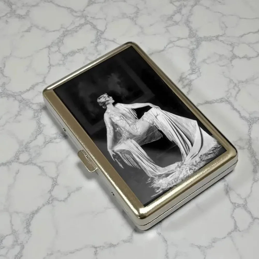 A vintage snap metal card holder displaying a black and white photograph of a draped figure.