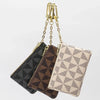 A geometric mini coin purse in beige and black patterned fabric with a gold chain.