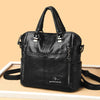 A black leather fashionable crossbody backpack bag with silver hardware displayed on a light surface.