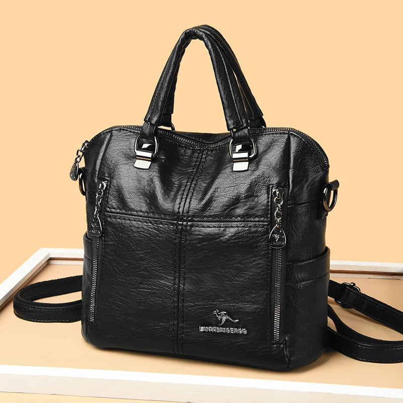 A black leather fashionable crossbody backpack bag with silver hardware displayed on a light surface.