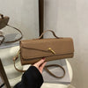 A tan crocodile-embossed PU leather clutch bag with a gold clasp displayed on a white pedestal.