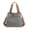 A gray canvas tote bag with brown leather straps and a zipper closure.