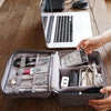 A gray leather cable storage organizer bag is open on a wooden table, showing various electronic cables and accessories.