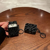 Une coque de protection noire à motif zèbre, à côté d'un écouteur AirPods Pro sur une surface en bois.
