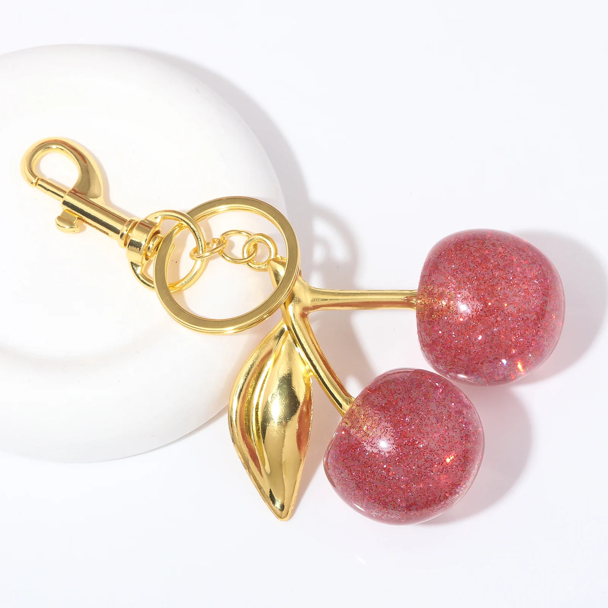 Gold-toned keychain featuring two round, glittery pink crystal fruit charms against a white background.