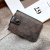A dark brown PU leather card holder purse resting on a light gray knitted fabric next to a piece of paper.