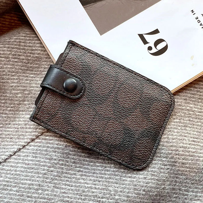 A dark brown PU leather card holder purse resting on a light gray knitted fabric next to a piece of paper.