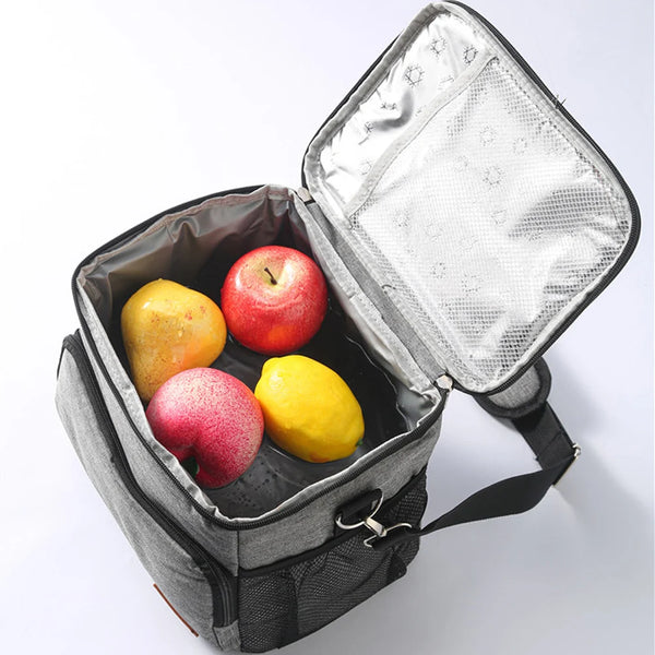Une sac isotherme argenté ouvert, révélant trois pommes fraîches et un citron jaune à l'intérieur.