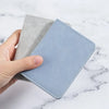A hand holds a light blue ultra-thin multi-slot card wallet next to a gray one on a white marble surface.