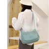 A woman wearing a white shirt and straw hat is shown from the back carrying a light blue waterproof nylon crossbody shoulder 