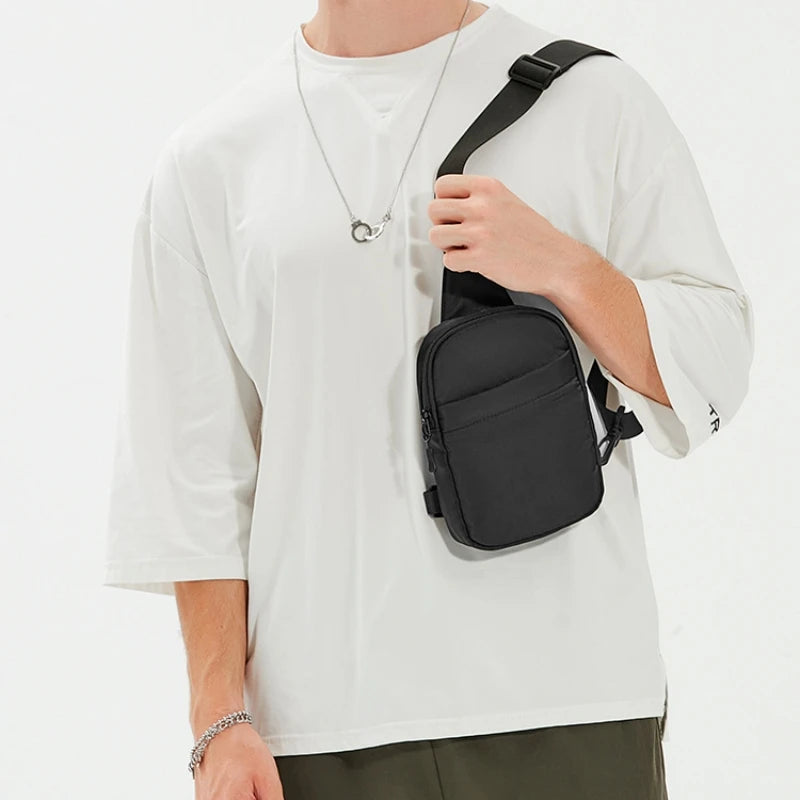 Una persona lleva una camiseta blanca y sostiene un bolso cruzado negro multifuncional.
