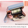 A light blue compact PU leather wallet with a zippered coin pocket and card slots, shown open on a pink background.