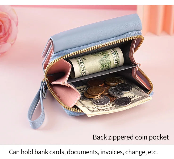 A light blue compact PU leather wallet with a zippered coin pocket and card slots, shown open on a pink background.