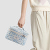 A light blue quilted cotton makeup organizer set being held by a person next to beige pants.