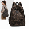 A brown leopard print laptop backpack with black padded straps shown next to a woman.