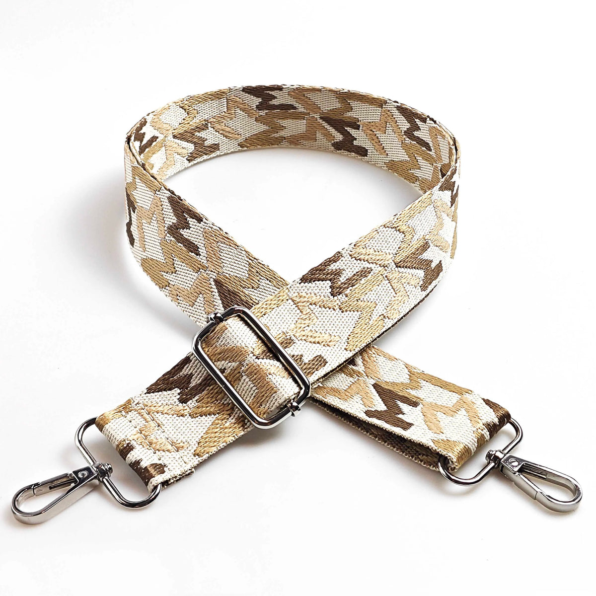 A beige and brown jacquard patterned adjustable crossbody bag strap with silver hardware.