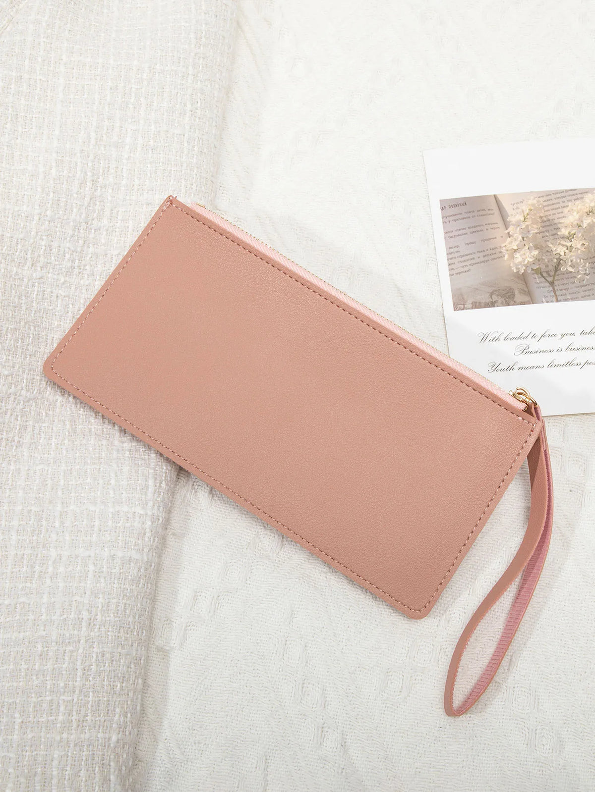 A pale pink elegant PU leather coin purse and card holder resting on a white textured fabric.