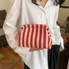 A white shirt sleeve holds a red and cream striped crochet tote bag with a shell accent.