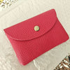 A vibrant pink genuine leather card holder with a gold-toned snap closure resting on a white textured surface.