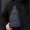 A navy blue lightweight nylon crossbody sling bag is shown being held against a black jacket.