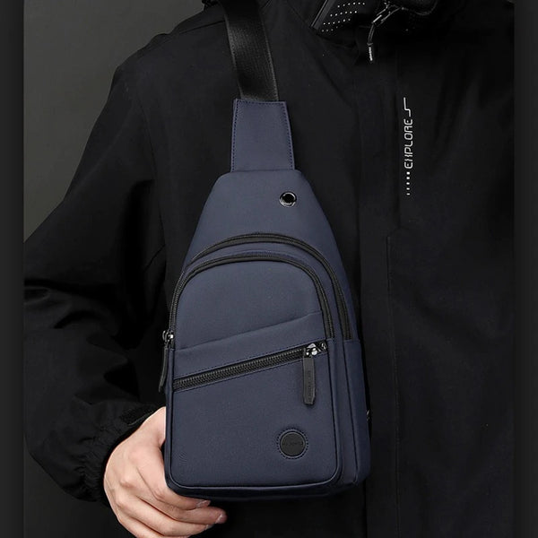 Dunkelblaue Nylon-Crossbody-Sling-Tasche wird gegen eine schwarze Jacke gehalten.