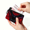 Eine Hand hält eine schwarze durchsichtige Tasche mit rotem und schwarzem Design neben Papiergeld.
