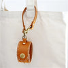 A vintage brown leather glove holder strap attached to a white fabric bag.